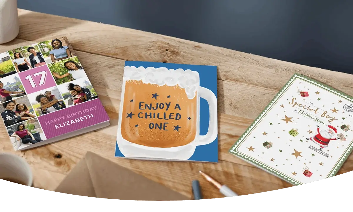 Selection of greeting cards including personalised photo cards, a character-themed birthday card, and a humorous birthday card displayed on a wooden table. Selection of greeting cards including personalised photo cards, a character-themed birthday card, and a humorous birthday card displayed on a wooden table.