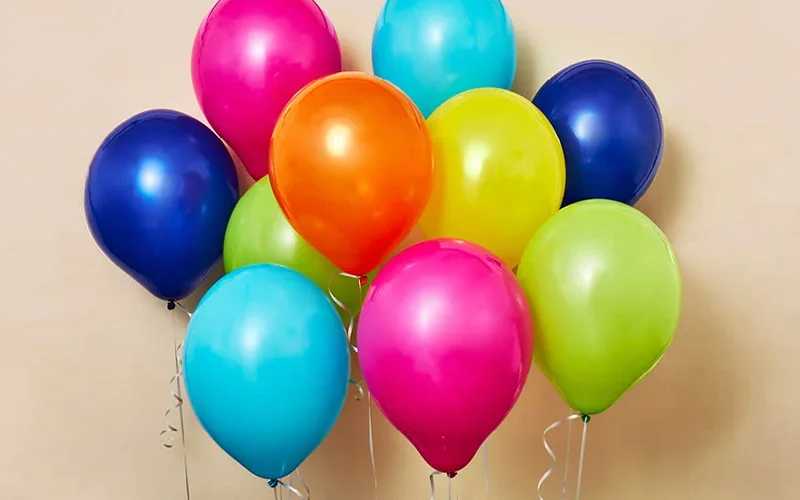 A cluster of brightly coloured latex balloons in pink, blue, green, yellow and orange, gathered together with curled ribbon tails. The balloons are displayed against a neutral background, creating a vibrant decoration for a birthday celebration or party. A cluster of brightly coloured latex balloons in pink, blue, green, yellow and orange, gathered together with curled ribbon tails. The balloons are displayed against a neutral background, creating a vibrant decoration for a birthday celebration or party.