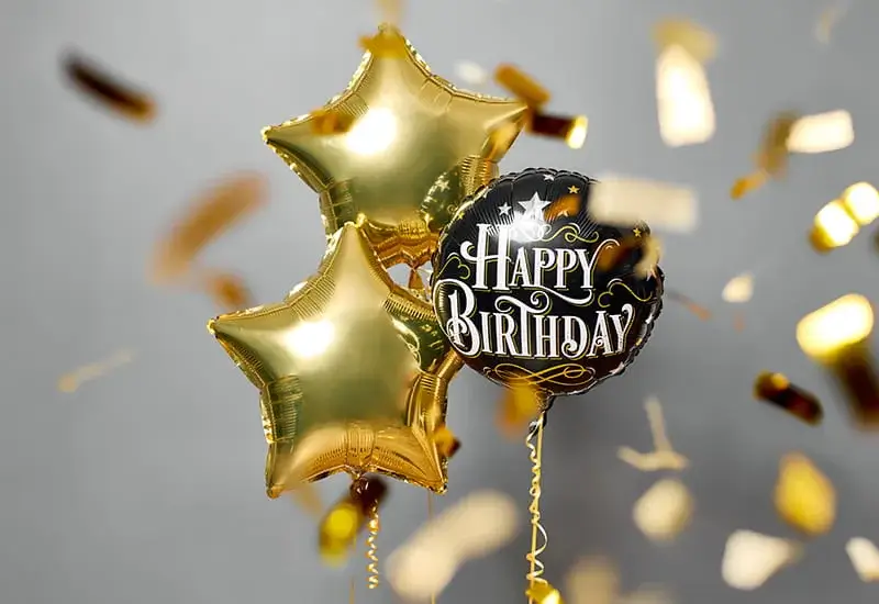 Three gold star balloons and a black balloon reading Happy Birthday float among falling gold confetti against a light background. Three gold star balloons and a black balloon reading Happy Birthday float among falling gold confetti against a light background.