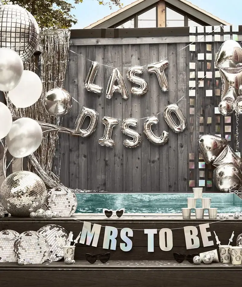 Hen party display with silver disco balls, metallic balloons, Last Disco and Mrs To Be decorations arranged around an outdoor pool area. Hen party display with silver disco balls, metallic balloons, Last Disco and Mrs To Be decorations arranged around an outdoor pool area.