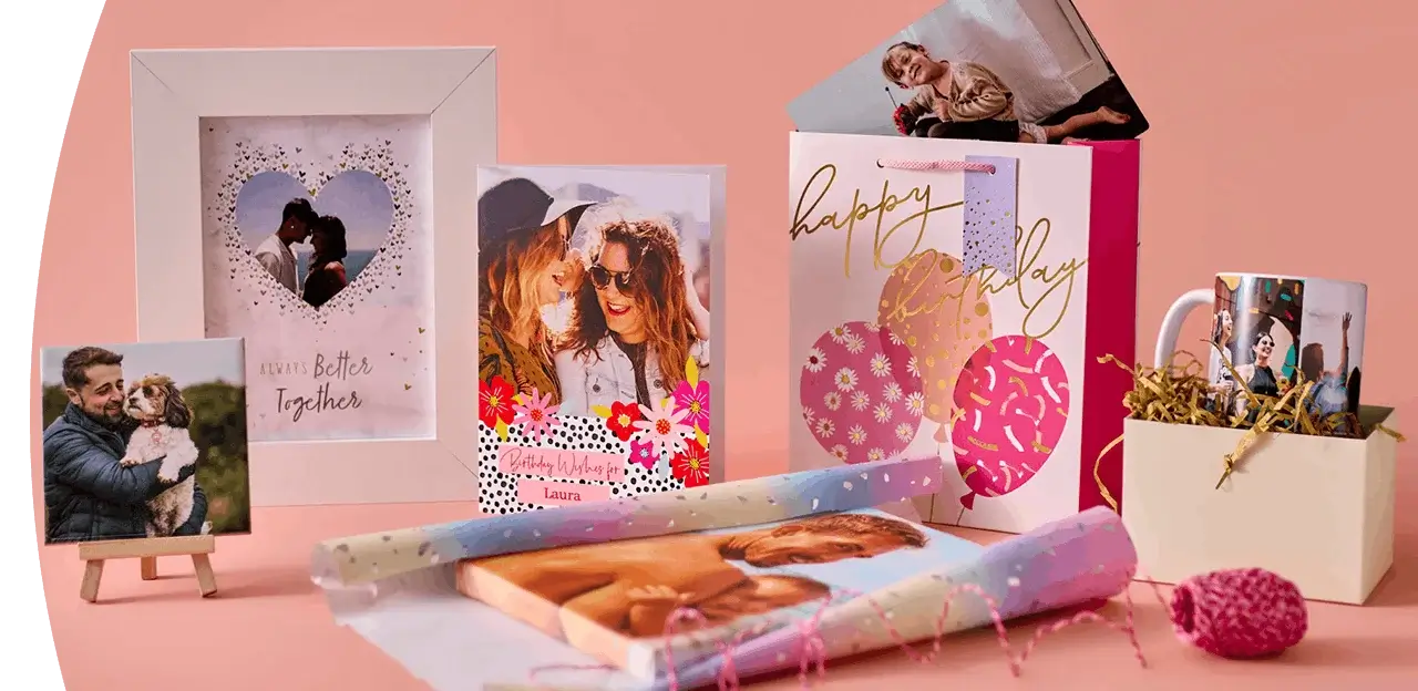 Personalised gift collection featuring photo prints, a framed keepsake, a birthday gift bag, custom mugs, and personalised wrapping paper on a pink background.
