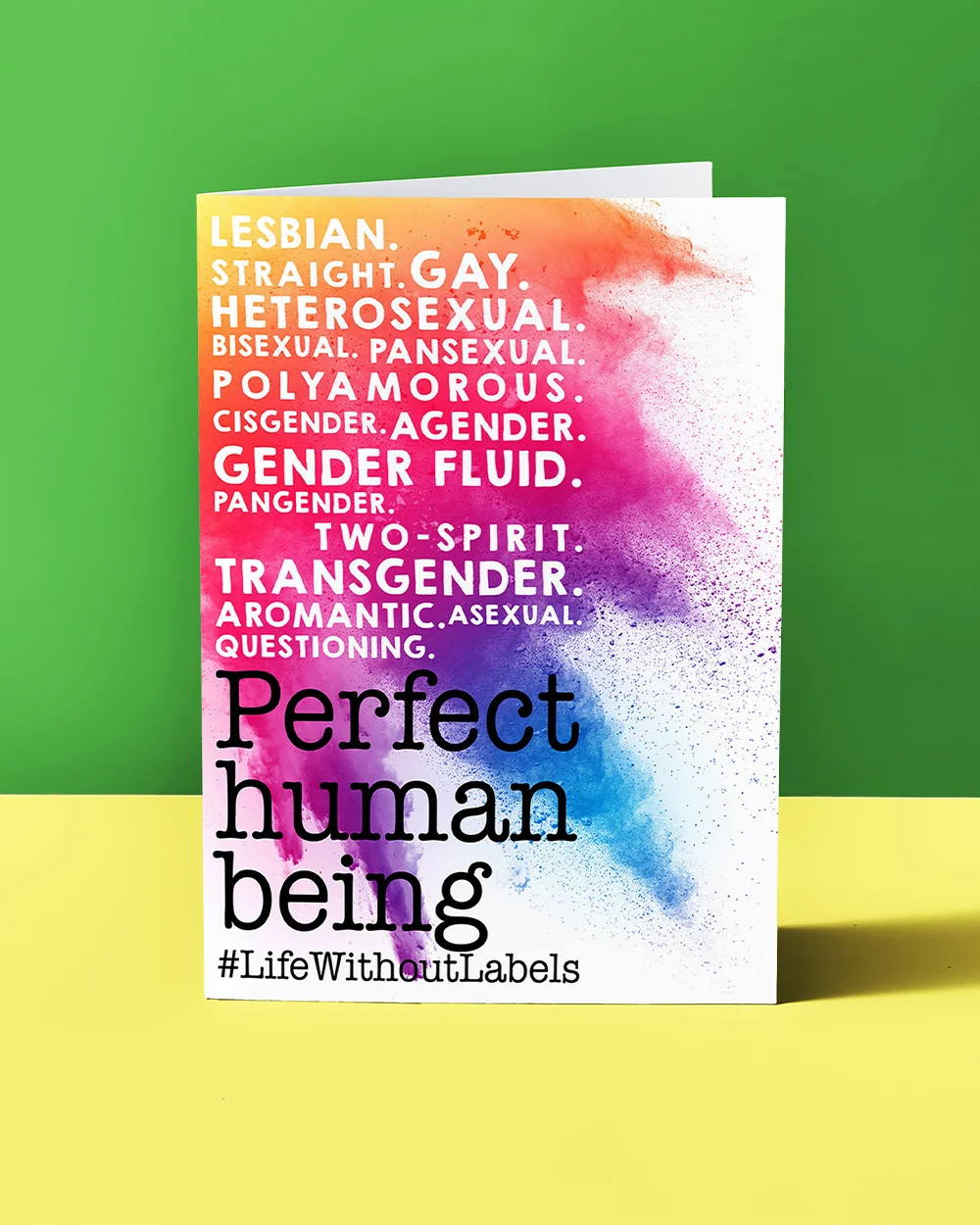A Pride greeting card with a colourful paint‑splash background listing identities including ‘Lesbian,’ ‘Gay,’ ‘Bisexual,’ ‘Transgender,’ and ‘Asexual,’ with large black text at the bottom reading ‘Perfect human being’ and ‘#LifeWithoutLabels.’