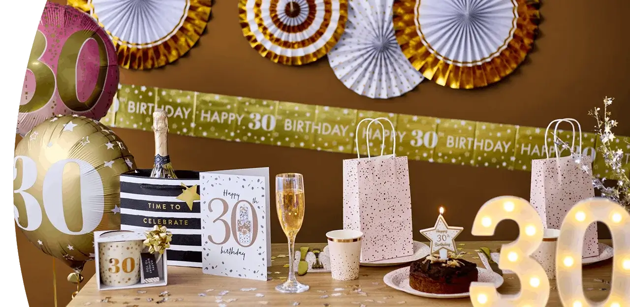 30th birthday celebration table with balloons, a birthday banner, champagne glass, gift bags, birthday cake, and gold party decorations. 30th birthday celebration table with balloons, a birthday banner, champagne glass, gift bags, birthday cake, and gold party decorations.