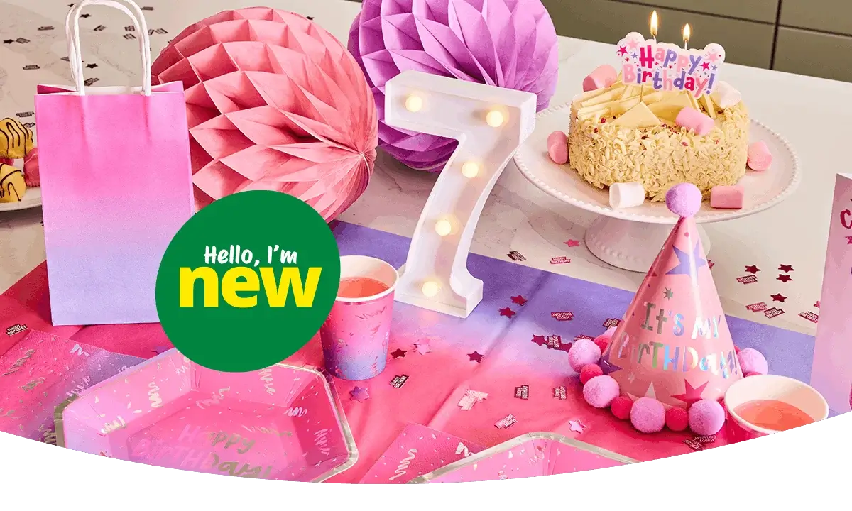 Pink and purple birthday party table setup with a lit number 7 decoration, birthday cake, gift bag, party hat, cups, plates, and festive paper decorations on a colorful tablecloth. Pink and purple birthday party table setup with a lit number 7 decoration, birthday cake, gift bag, party hat, cups, plates, and festive paper decorations on a colorful tablecloth.