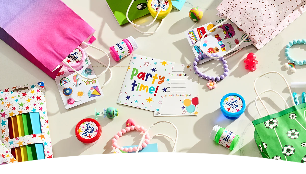 A flat-lay display of children's party bag fillers and party accessories arranged on a light background, featuring colourful ‘Party Time!’ invitations, mini gift bags, bubble tubs, slime tubs, modelling dough, sticker sheets, bead bracelets, small toys and novelty party favours. A football-themed party bag, bright pink gift bag and packs of crayons are also included, showcasing a variety of party bag ideas for children's celebrations. A flat-lay display of children's party bag fillers and party accessories arranged on a light background, featuring colourful ‘Party Time!’ invitations, mini gift bags, bubble tubs, slime tubs, modelling dough, sticker sheets, bead bracelets, small toys and novelty party favours. A football-themed party bag, bright pink gift bag and packs of crayons are also included, showcasing a variety of party bag ideas for children's celebrations.