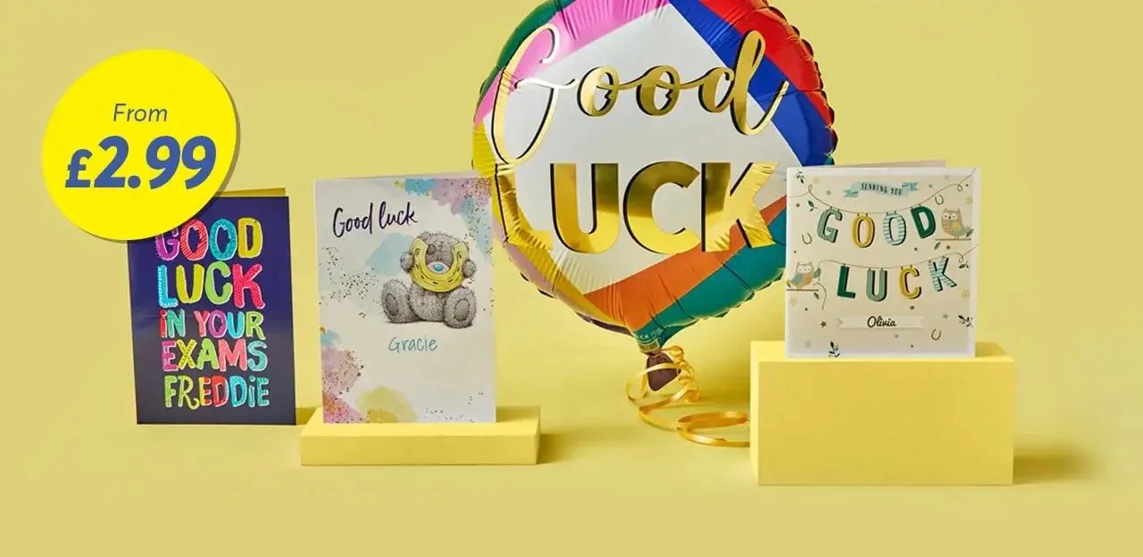 'The image shows a yellow background with three good luck cards and a colorful balloon. The first card on the left reads 'GOOD LUCK IN YOUR EXAMS FREDDIE' in multicolored letters. The middle card features a teddy bear and says 'Good Luck Gracie'. The third card on the right has the text 'GOOD LUCK Olivia' with decorative elements. A large, round balloon with rainbow colors and gold text saying 'Good Luck' is positioned behind the cards.'