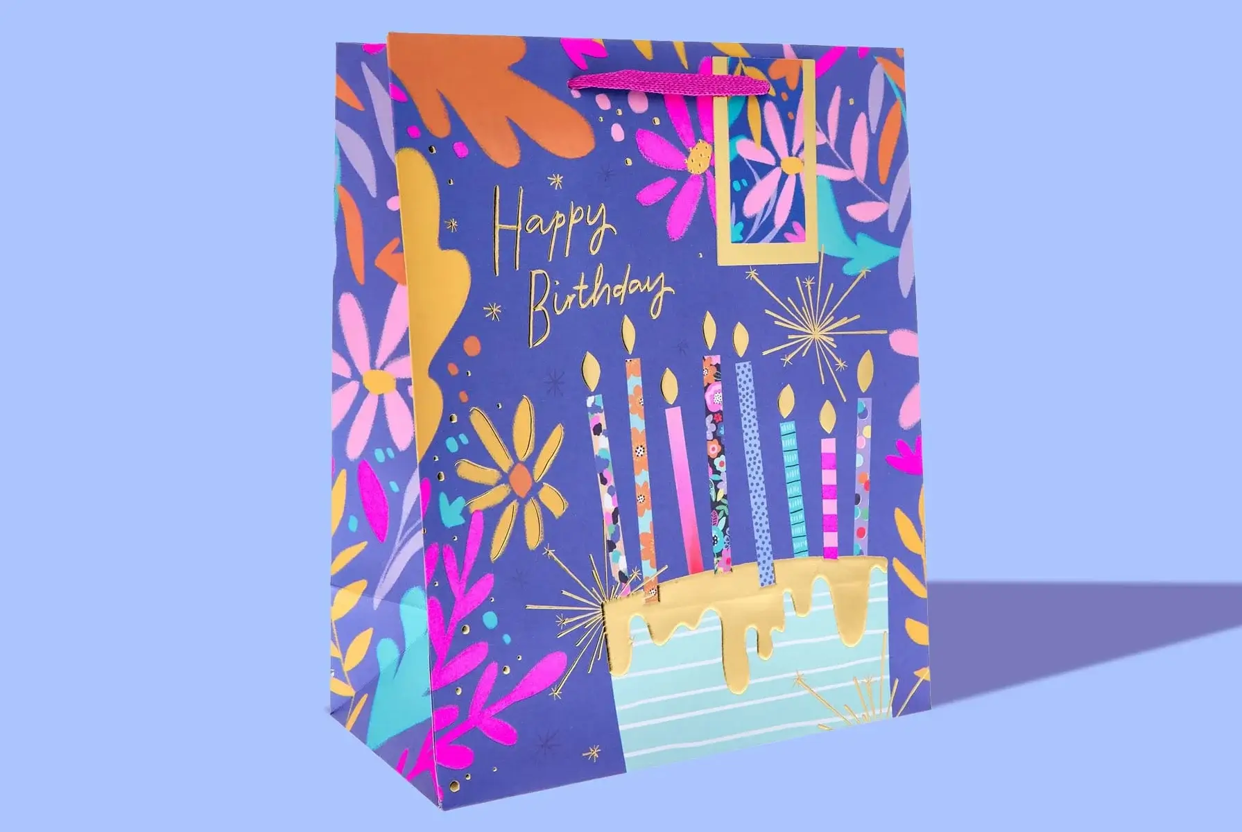 'A colorful birthday gift bag with a purple background, decorated with various flowers and stars. The front of the bag features the text 'Happy Birthday' in gold letters and an illustration of a cake with six lit candles, each candle having different patterns and colors. The bag has pink handles at the top.' 'A colorful birthday gift bag with a purple background, decorated with various flowers and stars. The front of the bag features the text 'Happy Birthday' in gold letters and an illustration of a cake with six lit candles, each candle having different patterns and colors. The bag has pink handles at the top.'