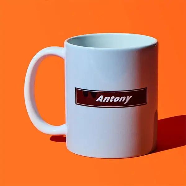 White ceramic mug on an orange background featuring a personalised name label reading Antony