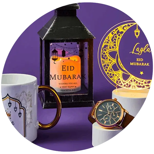 White ceramic mug with a gold handle, decorated with an arch design, hanging lanterns, and intricate patterns, featuring Eid Mubarak text on a purple background.