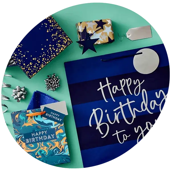 Blue-toned birthday gift wrap set with striped gift bag, matching cards, and wrapped presents on a green background