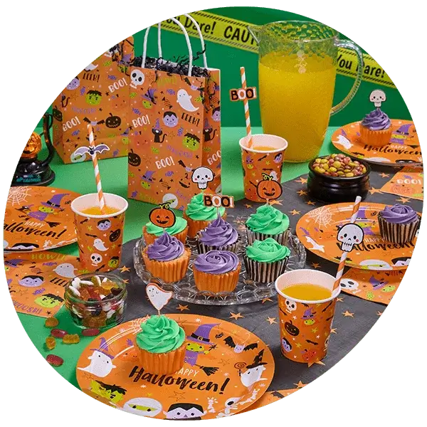 Halloween party table with themed plates, cupcakes, candy, and decorations including 'BOO' designs and caution tape.