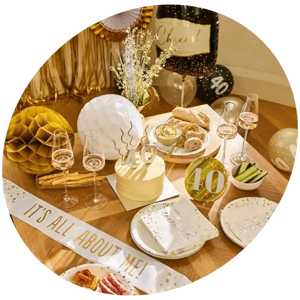 40th birthday celebration table with a birthday cake, number 40 decorations, champagne glasses, balloons, party food, and gold-and-white birthday décor.