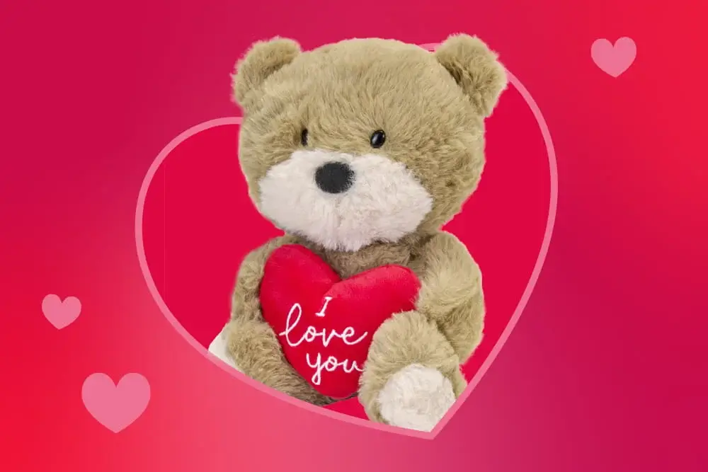 Cute brown teddy bear holding a red heart that reads I love you, set against a pink background with scattered hearts.