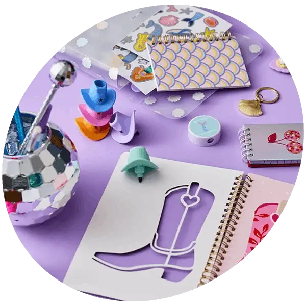 Western-themed stationery set with notebooks, stickers, mini cowboy boot accessories, pens, and a mirrored pen holder on a pastel purple background.