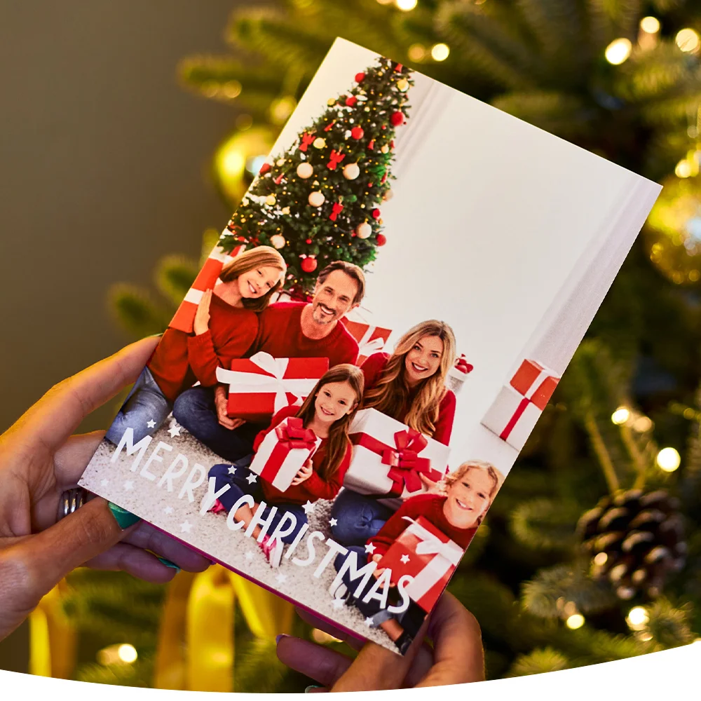 Christmas card showing a family of five in red sweaters holding gifts, with a decorated tree in the background and 'Merry Christmas' text at the bottom.
