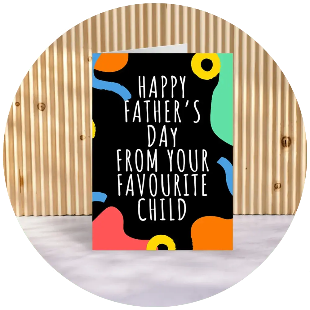 A greeting card with a colorful abstract design featuring shapes in blue, yellow, green, red, and orange on a black background. The text on the card reads 'HAPPY FATHER'S DAY FROM YOUR FAVOURITE CHILD'. The card is displayed against a wooden backdrop. A greeting card with a colorful abstract design featuring shapes in blue, yellow, green, red, and orange on a black background. The text on the card reads 'HAPPY FATHER'S DAY FROM YOUR FAVOURITE CHILD'. The card is displayed against a wooden backdrop.