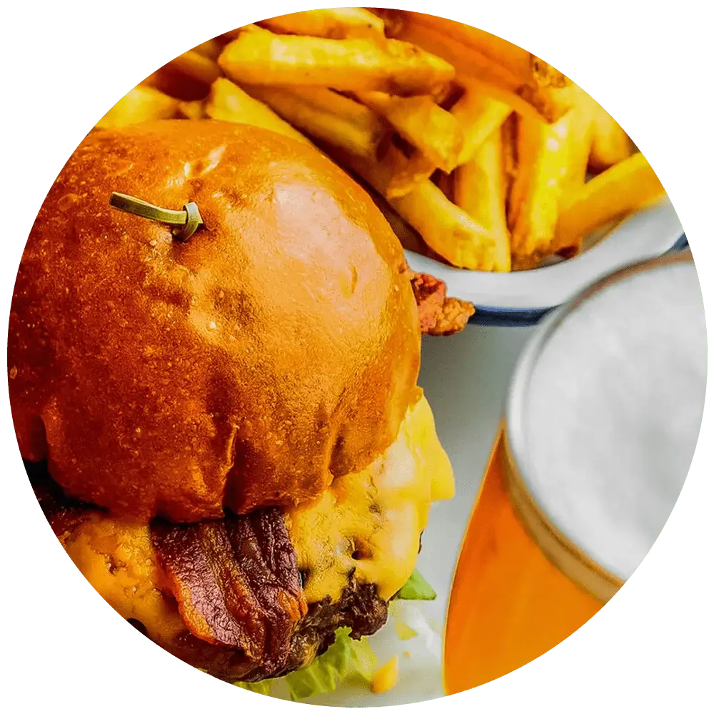 A close-up image of a cheeseburger with bacon, lettuce, and a toasted bun. The burger is accompanied by a side of golden French fries in a white bowl and a glass of beer with foam on top.' A close-up image of a cheeseburger with bacon, lettuce, and a toasted bun. The burger is accompanied by a side of golden French fries in a white bowl and a glass of beer with foam on top.'