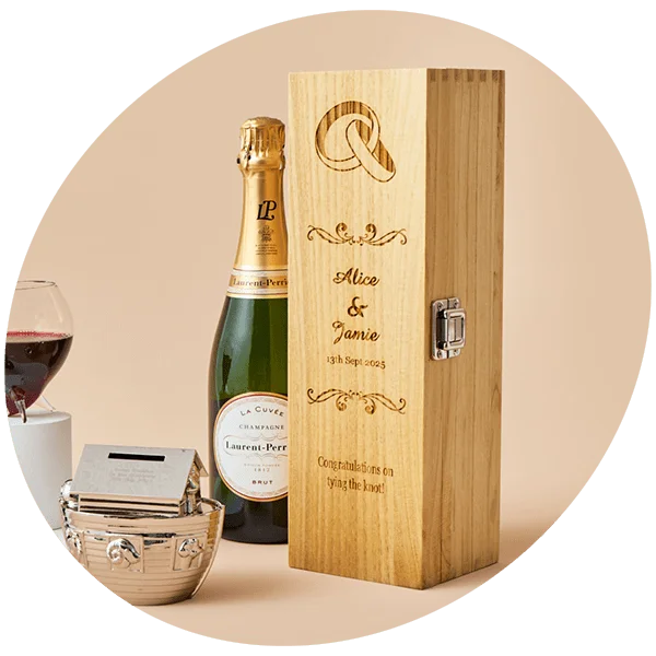 Wooden gift box engraved with intertwined rings, the names Alice and Jamie, the date 13th Sept 2025, and the message Congratulations on tying the knot, displayed with a bottle of Laurent-Perrier champagne, a glass of red wine, and a small silver chest.