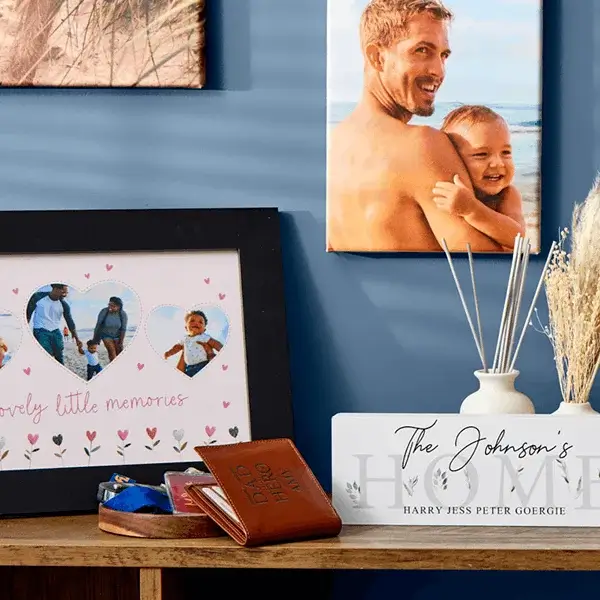 Personalised home décor display featuring framed photo prints, a custom family sign, reed diffuser, and engraved wallet arranged on a wooden shelf.