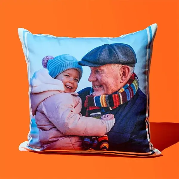 Square cushion on an orange background featuring a printed photo of an adult holding a child outdoors in winter clothing