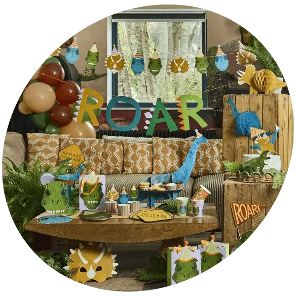 Dinosaur themed children’s party setup with decorations, balloons, tableware, and a ROAR banner in a garden setting