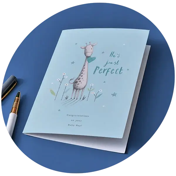 Baby boy congratulations card featuring a giraffe illustration and star details, displayed against a blue background with a pen nearby.