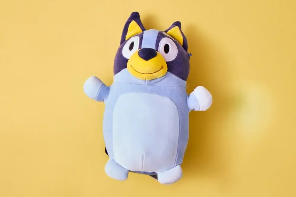 Blue cartoon dog plush toy with yellow snout and dark blue ears, shown against a yellow background. Blue cartoon dog plush toy with yellow snout and dark blue ears, shown against a yellow background.