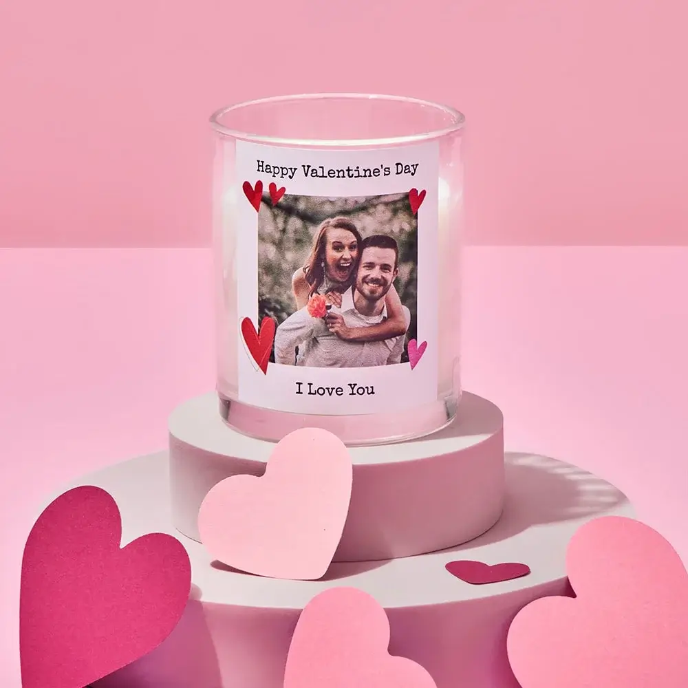 Black photo frame with a heart-shaped cutout at the top and three smaller rectangular photos below, featuring the text Bryan and Jen on a white background, set against a pink backdrop with heart shapes.