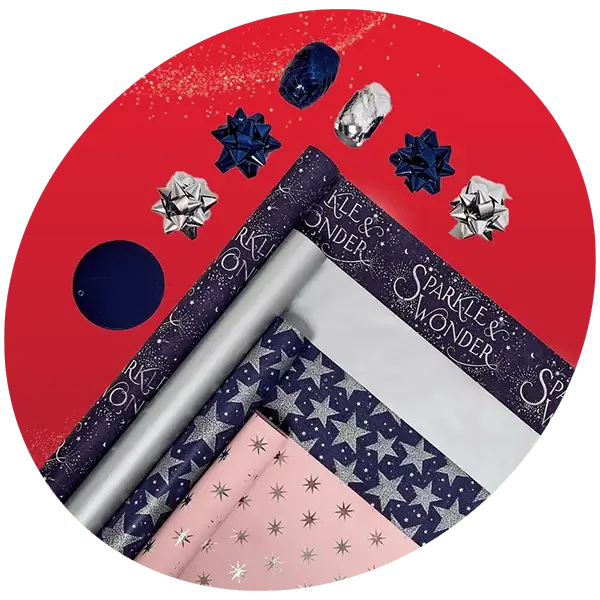 Festive wrapping paper and bows on a red background with blue and pink star-patterned rolls, silver foil, and Sparkle & Wonder text.