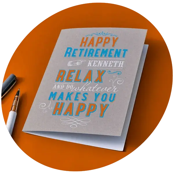 A retirement card with colourful decorative lettering reading Happy Retirement Kenneth, Relax and Do Whatever Makes You Happy is displayed on an orange surface beside two pens.
