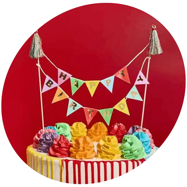 Colourful birthday cake with rainbow piping and a two-tier Happy Birthday bunting topper on a red background