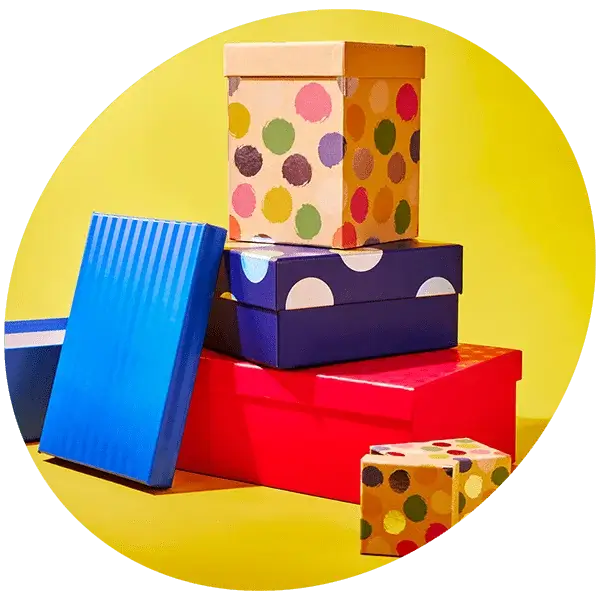 Stack of colorful gift boxes with polka dots and stripes against a bright yellow background.