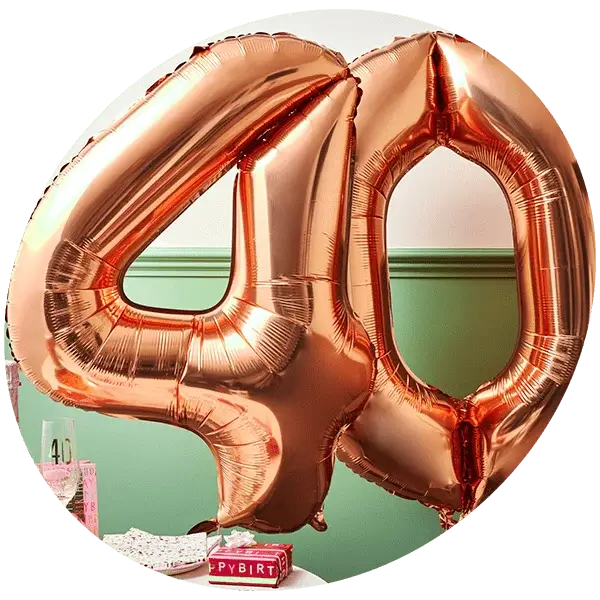 Two large, metallic rose gold balloons shaped as the number 40 are prominently displayed against a green and white wall background. The balloons are reflective and shiny, indicating a celebratory event, likely a 40th birthday or anniversary.