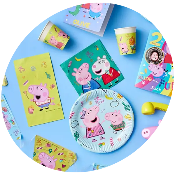 A collection of Peppa Pig themed party supplies including plates, cups, napkins, party bags and a personalised card arranged on a light blue background.