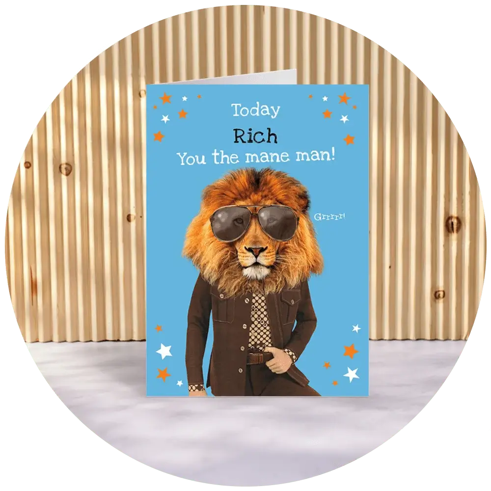 A greeting card with a blue background featuring an illustration of a lion wearing sunglasses and a brown suit. The text on the card reads, 'Today Rich You the mane man!' and there is a small speech bubble next to the lion that says, 'Grrr!'. The background of the image shows a corrugated metal wall.' A greeting card with a blue background featuring an illustration of a lion wearing sunglasses and a brown suit. The text on the card reads, 'Today Rich You the mane man!' and there is a small speech bubble next to the lion that says, 'Grrr!'. The background of the image shows a corrugated metal wall.'
