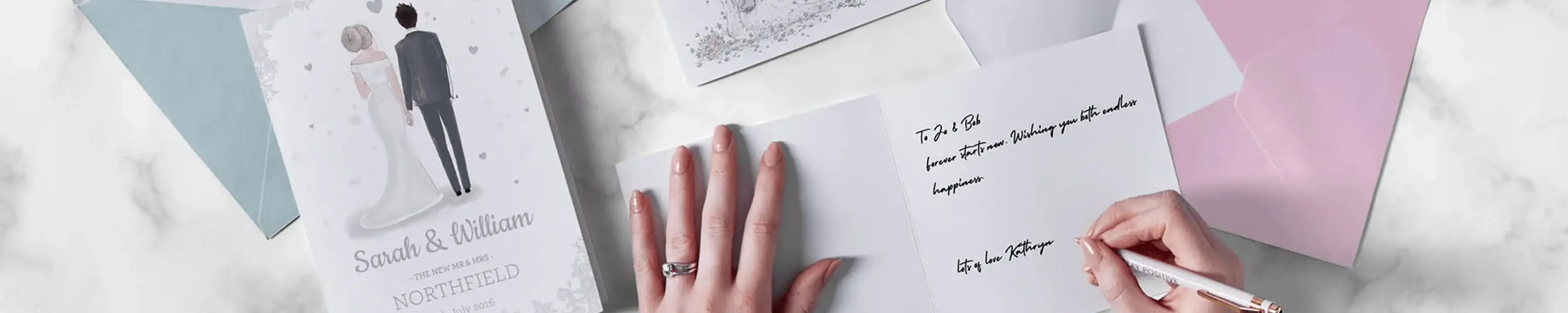 A person's hand is writing in a card with the text 'It's the love between two people who grow closer and closer. It's so unique.' The card is surrounded by other cards, including one with an illustration of a bride and groom and the names 'Sarah & William' along with the date '10/09/2023'. A person's hand is writing in a card with the text 'It's the love between two people who grow closer and closer. It's so unique.' The card is surrounded by other cards, including one with an illustration of a bride and groom and the names 'Sarah & William' along with the date '10/09/2023'.