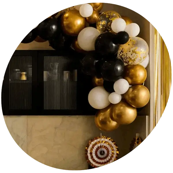 Black, gold and white balloon arch display with confetti balloons and party decorations for a milestone birthday celebration.