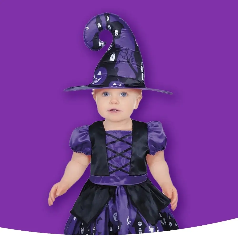 A child in a purple and black witch costume with a pointed hat and lace-up dress, standing against a purple background