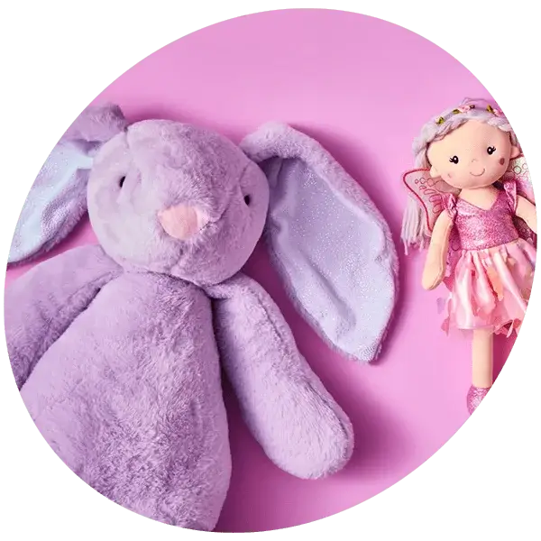 Plush purple bunny and small fairy doll in a pink dress with wings, lying on a pink background.