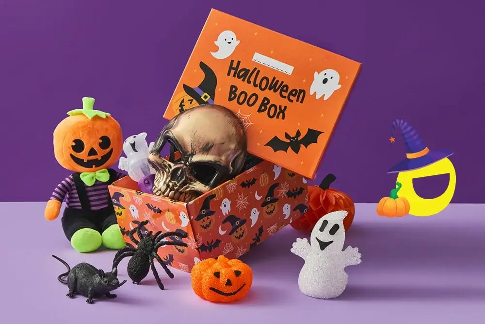 Halloween Boo Box filled with a metallic skull, ghost figure, and purple bat, surrounded by festive decorations including a plush pumpkin, glittery pumpkin, spider, rat, and ghost on a purple background. Halloween Boo Box filled with a metallic skull, ghost figure, and purple bat, surrounded by festive decorations including a plush pumpkin, glittery pumpkin, spider, rat, and ghost on a purple background.
