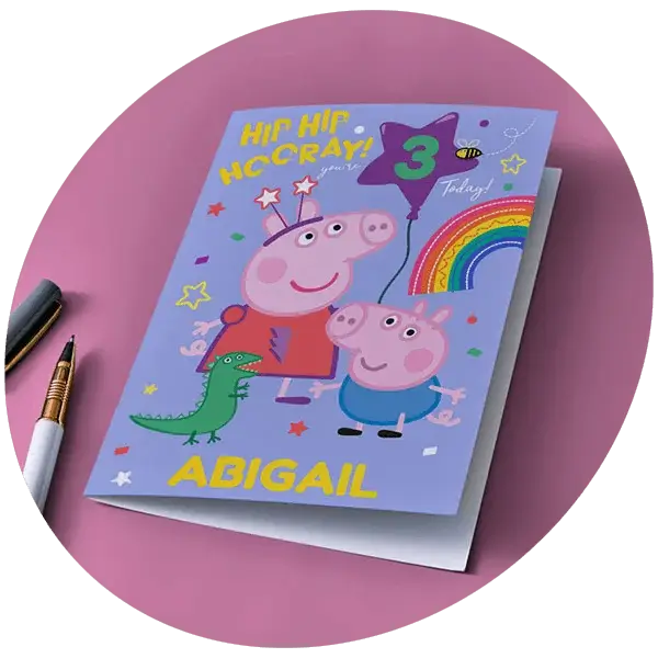 A bright birthday card with bold text and hand‑drawn pointing hands, being placed into a hot pink envelope against a yellow background.