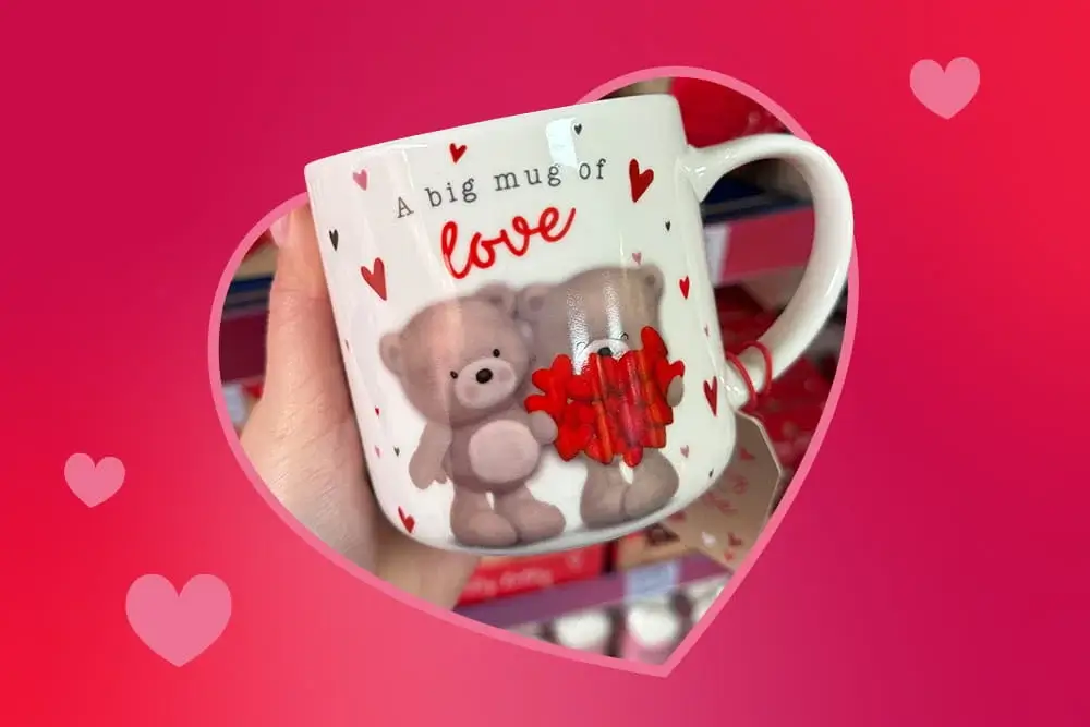 White mug decorated with two teddy bears and small red hearts, featuring the phrase a big mug of love.