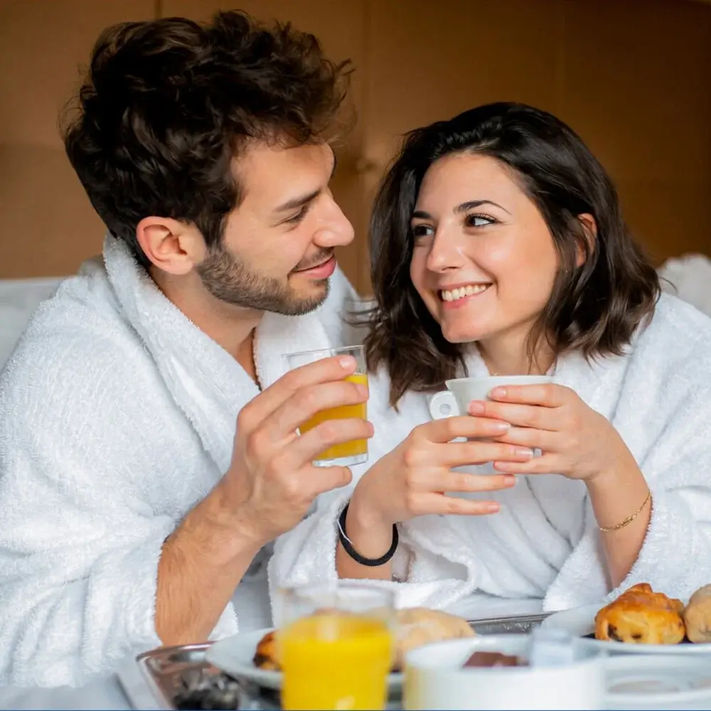 Red heart-shaped paper plates with a matching napkin, surrounded by red plastic cutlery, a striped straw, and scattered pink and red paper hearts on a pink background.