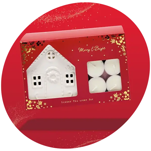 Red gift box with gold accents containing a white house-shaped tea light holder and four white tea light candles labeled Merry and Bright Luxury Tea Light Set. Red gift box with gold accents containing a white house-shaped tea light holder and four white tea light candles labeled Merry and Bright Luxury Tea Light Set.