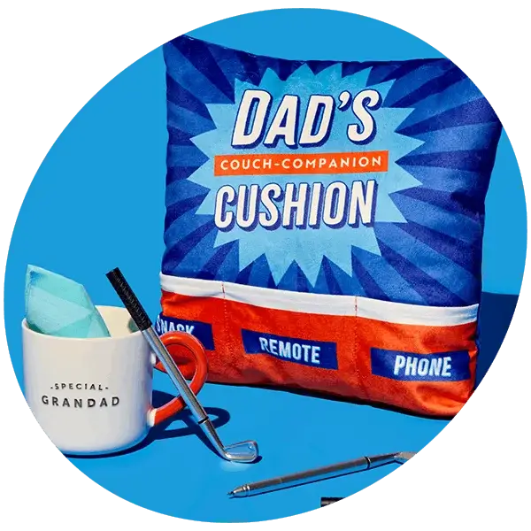 Blue Father’s Day cushion with Dad’s couch companion design alongside a mug, pens, and golf-themed items on a bright background