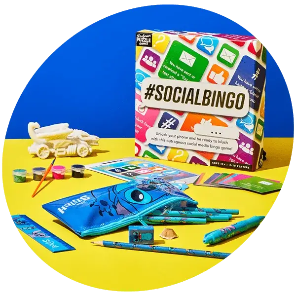 Colorful display of stationery and toys on a yellow and blue background featuring a #SOCIALBINGO game box, Stitch pencil case, pens, pencils, paint pots with brushes, bingo cards, and a small white airplane model