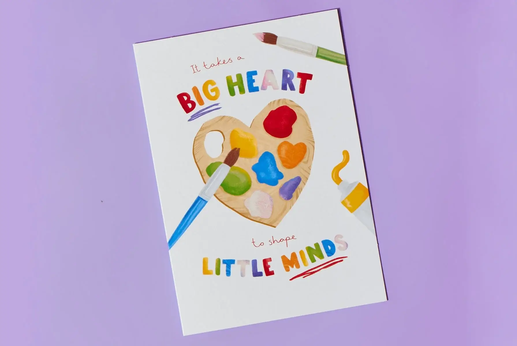 'A greeting card with a heart-shaped paint palette and colorful paint blobs, surrounded by two paintbrushes. The text reads: 'It takes a BIG HEART to shape LITTLE MINDS.' 'A greeting card with a heart-shaped paint palette and colorful paint blobs, surrounded by two paintbrushes. The text reads: 'It takes a BIG HEART to shape LITTLE MINDS.'