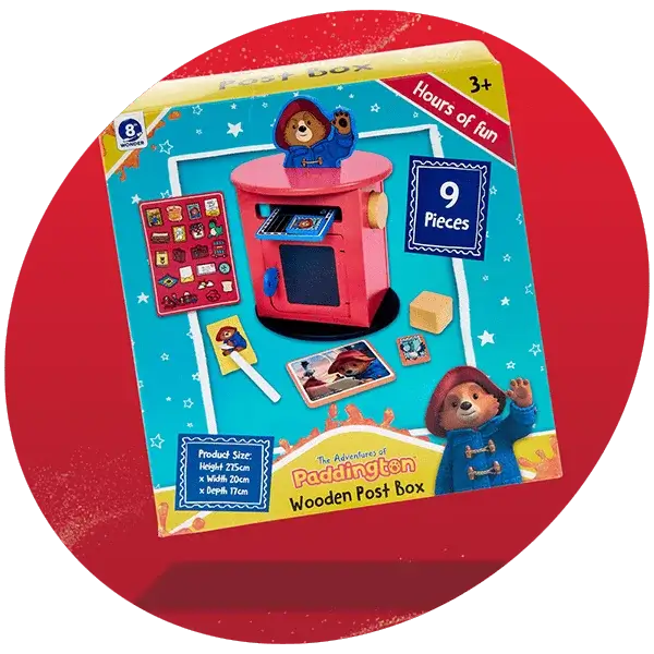 Colorful toy packaging for The Adventures of Paddington Wooden Post Box featuring a pink post box, Paddington Bear figure, and accessories, designed for children aged 3 and up with 9 pieces included and product dimensions of 25cm height, 20cm width, and 17cm depth.