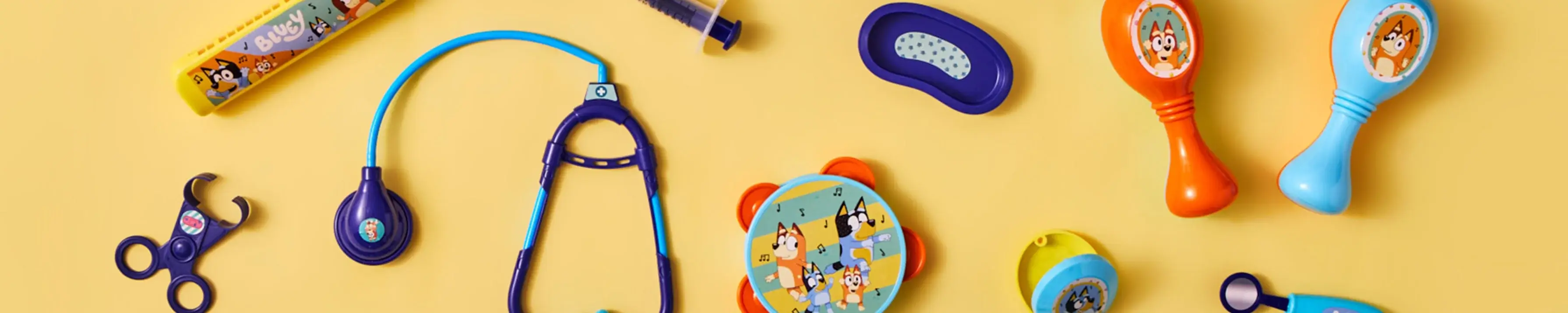 Bluey-themed children's toys including medical instruments and maracas, arranged on a yellow background. Bluey-themed children's toys including medical instruments and maracas, arranged on a yellow background.