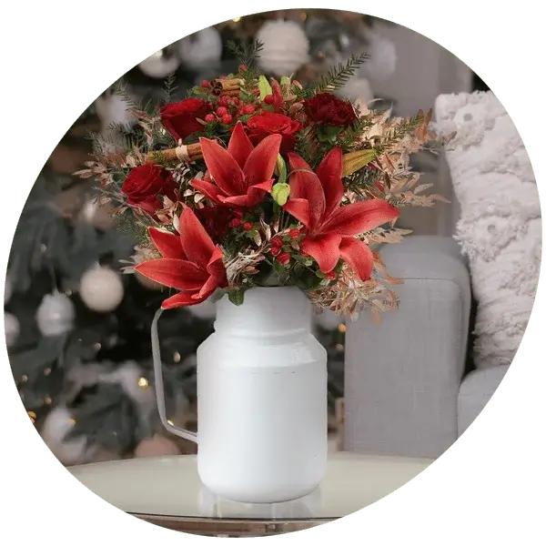 Bouquet with yellow roses, small white flowers, and green foliage arranged in a white pitcher.